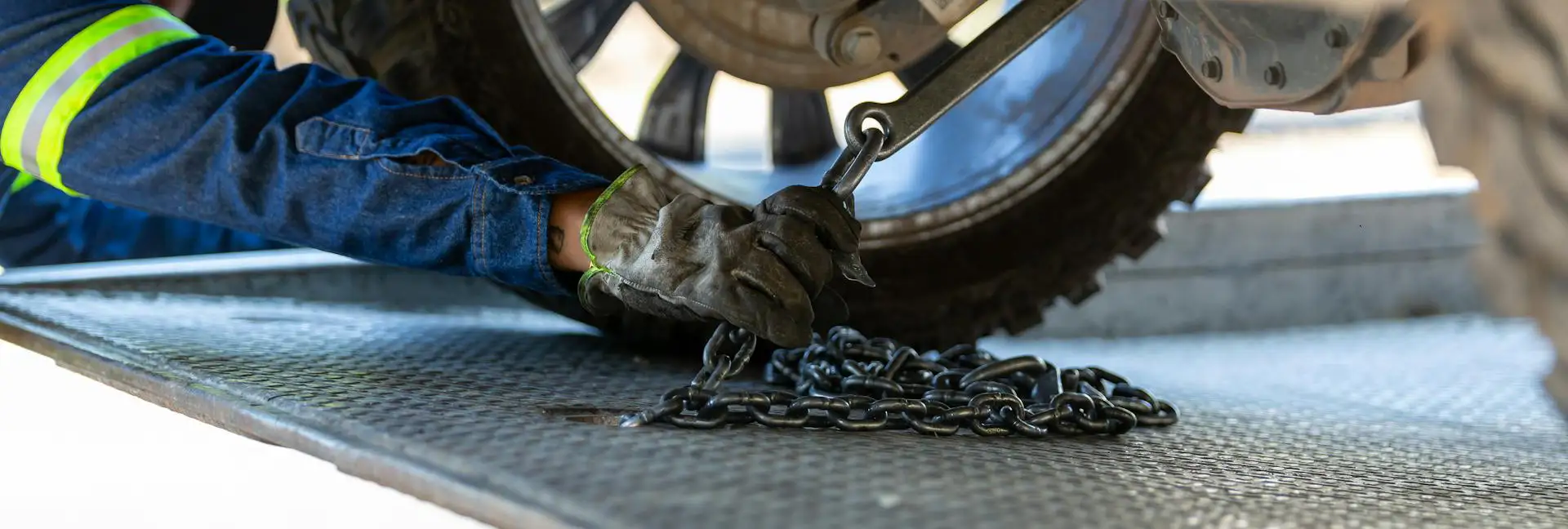 worker hooking vehicle to tow truck bed